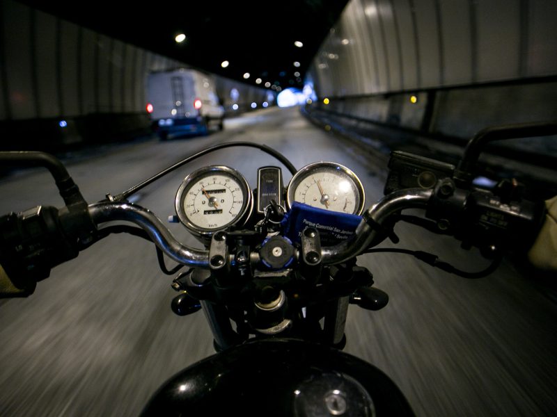 POV view of motorcycle driver driving through mountain road on high speed on vintage retro motorcycle or cafe racer, looks in rear view mirrors and control panel. concept adventure and roadtrip